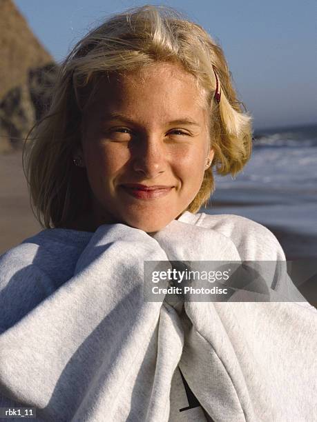 a blonde caucaian girl tries to keep warm at the beach and smiles - keep fotografías e imágenes de stock