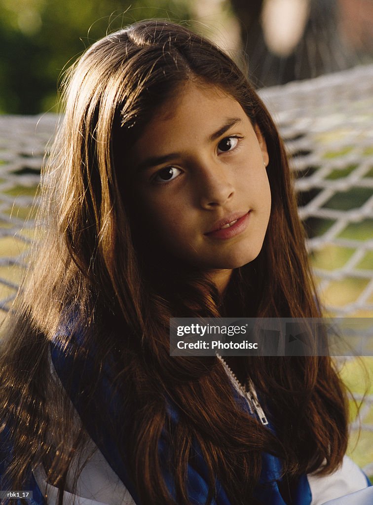 A pretty hispanic young woman sits with a shy smile on a hammock