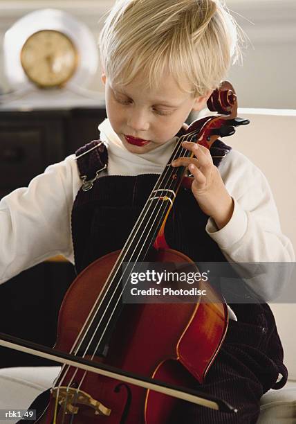 a small caucasian blonde child plays a string insturment - strings section stock pictures, royalty-free photos & images