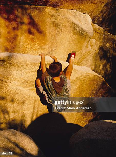 a caucasian boy rock climbs a cliff in golden sunlight - andersen stock pictures, royalty-free photos & images