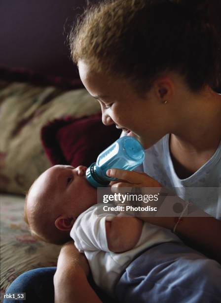 a caucasian older sister bottle feeds her little baby brother - sisters feeding bildbanksfoton och bilder