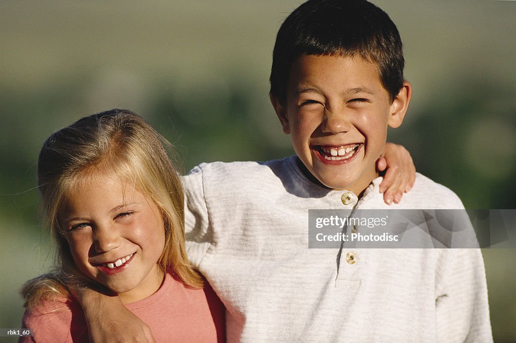 A caucasian boy and girl stand together with their arms around each other