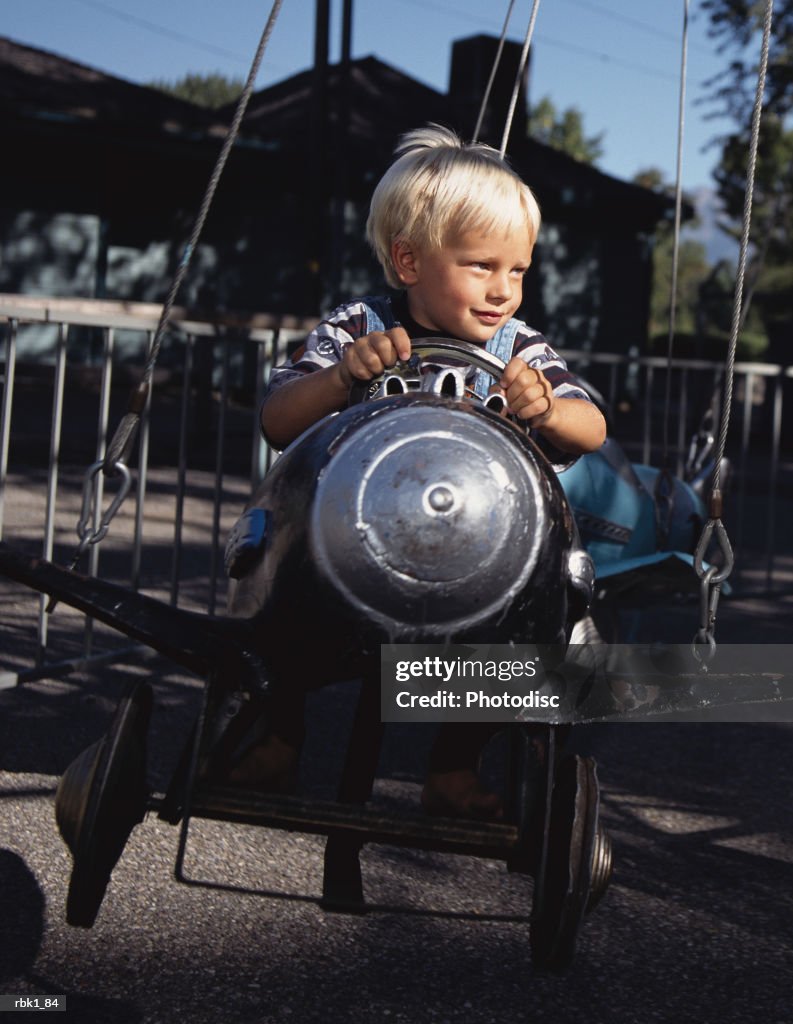 A caucasian blonde boy enjoys a plane ride at a park