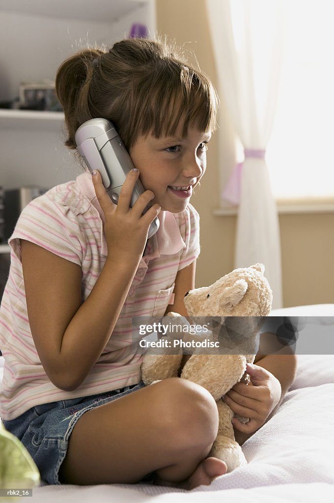 Lifestyle portrait of a female child in a pink striped shirt as she chats on the phone
