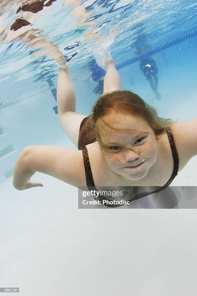 Underwater lifestyle shot of a female child in a swimsuit as she swims and plays in a pool