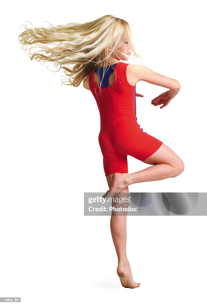 A little blonde girl in a red gymnastics outfit spins rapidly around as dances