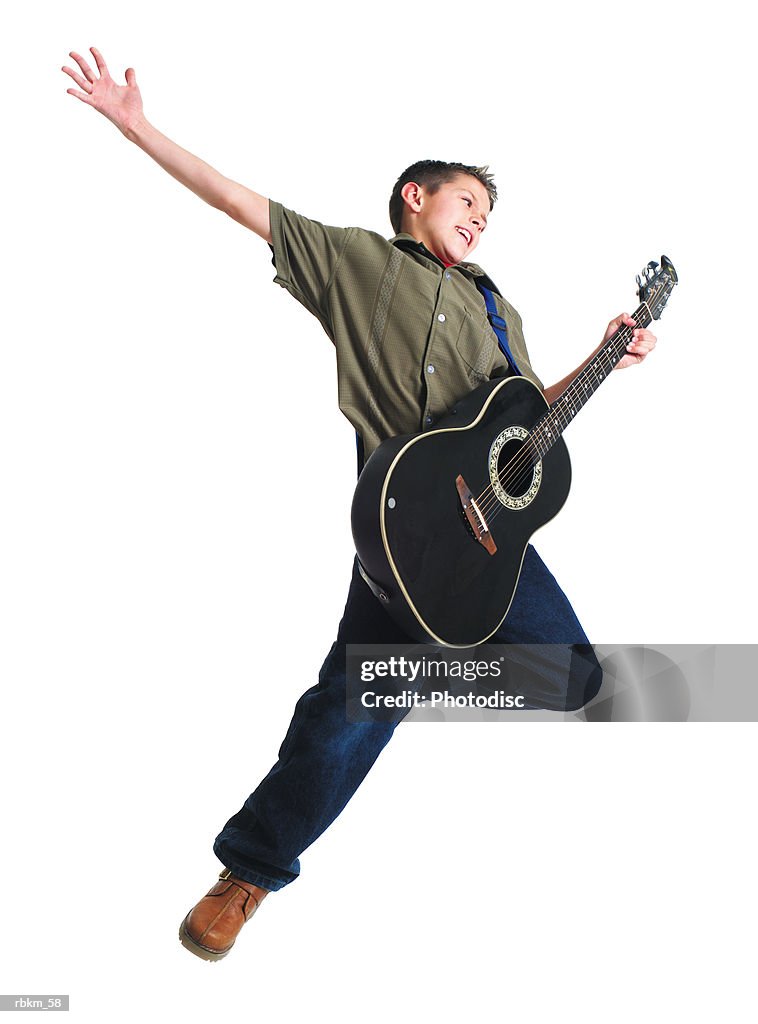 A young caucasian boy jumps into the air and throws his arm up while playing his guitar