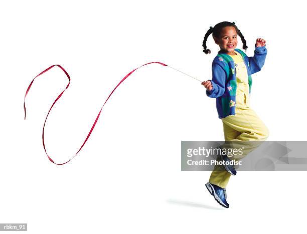 a cute little african american girl runs as she plays with a long ribbon - mens long jump stockfoto's en -beelden