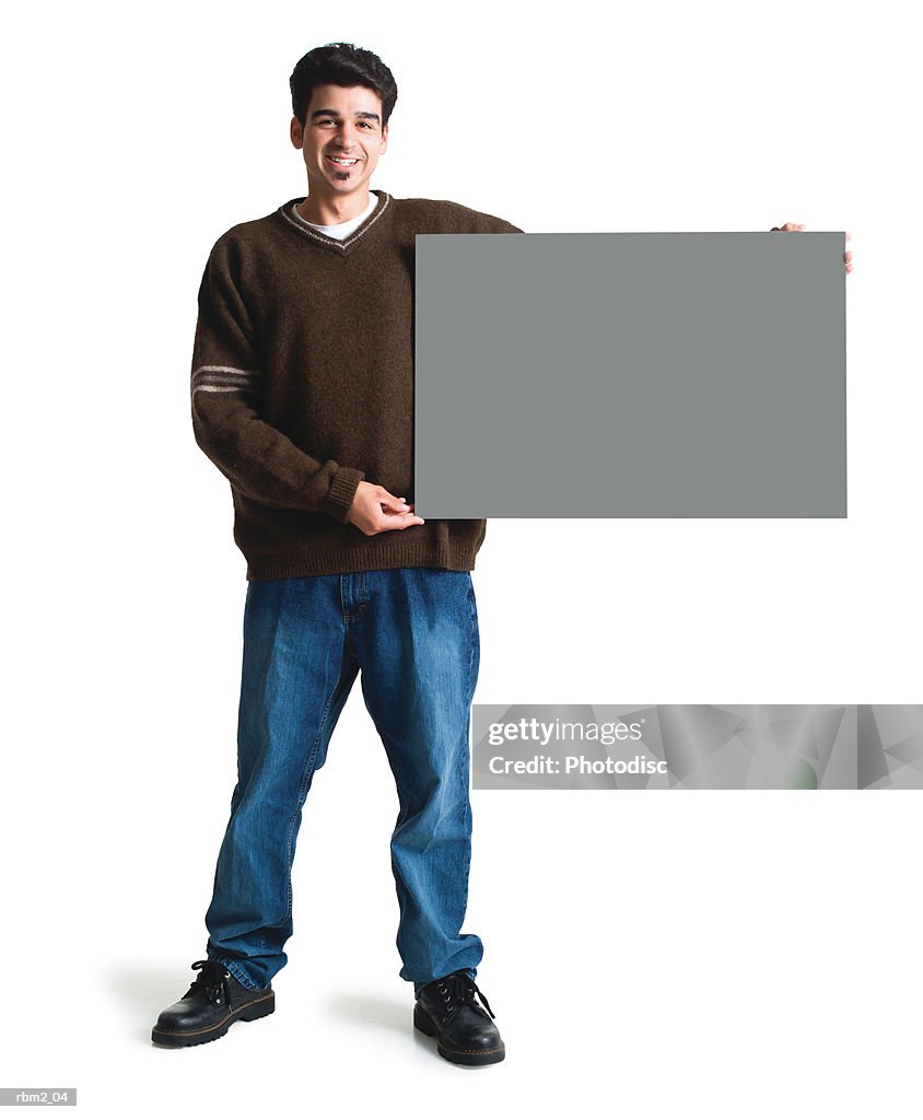 A young ethnic looking man in jeans and a brown sweater holds a large blank sing to his side