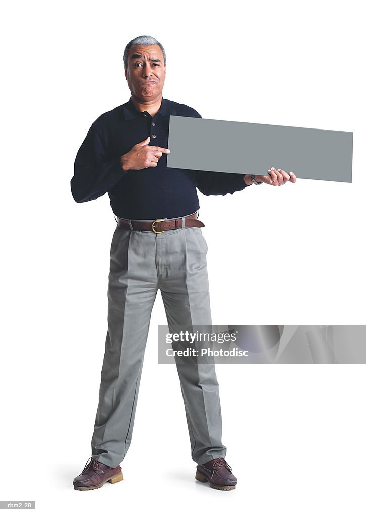 An elderly african american male in grey pants and a black shirt points to a  sign he is holding up