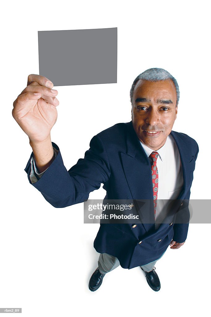 An older african american male in a jacket and tie holds up a  card as he smiles up at the camera