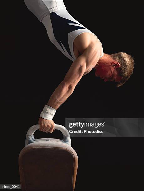 a strong male gymnast does a handstand on the pommel horse - voltigeerpaard stockfoto's en -beelden