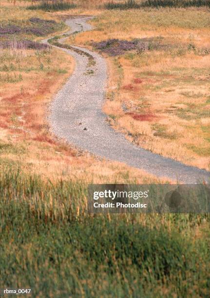 a old paved road winds back into the countryside through the fields on a bright fall day - fall back fotografías e imágenes de stock