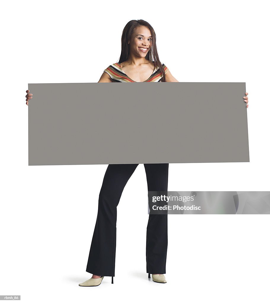 A young attractive african american girl in black pants and striped blouse holds a blank sign in front of her with both hands