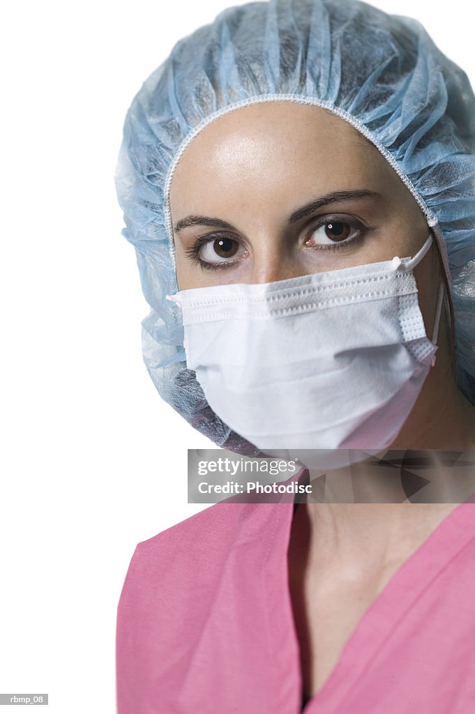 Portrait of a young adult female in pink scrubs and mask as she looks at the camera