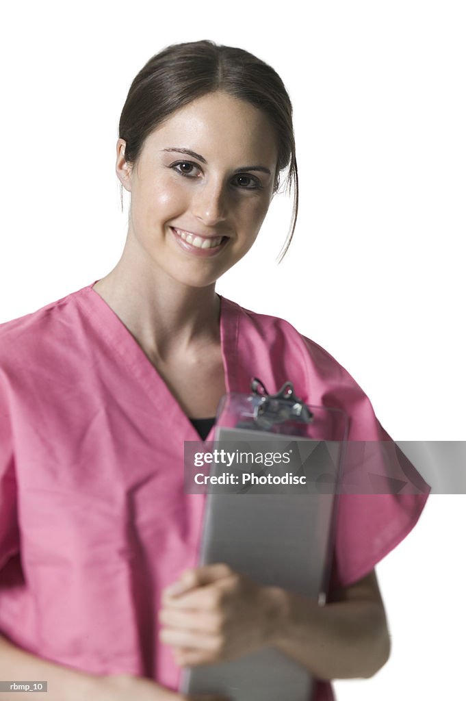 Portrait of a young adult female in pink scrubs as she holds her clipboard and smiles