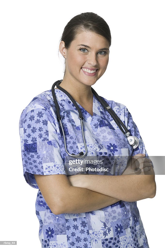 Portrait of a young adult female nurse in blue printed scrubs as she folds her arms and smiles