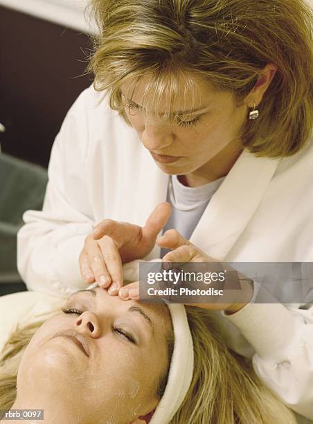 a young blonde woman gets a facial massage at a beauty salon - beauty salon foto e immagini stock