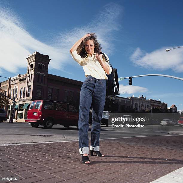 a young caucasian brunette woman strolls across the street in her small town - town imagens e fotografias de stock