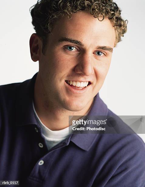 portrait of a young caucasian man in a purple shirt and curly hair as he smiles - curly stock pictures, royalty-free photos & images