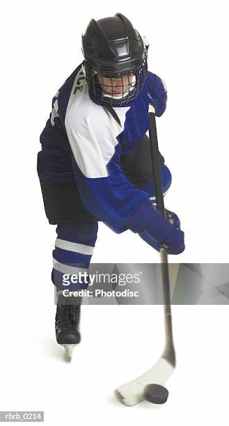 a child caucasian male hockey player dressed  in a blue white and black jersey skates with his stick and puck - ijshockeytenue stockfoto's en -beelden