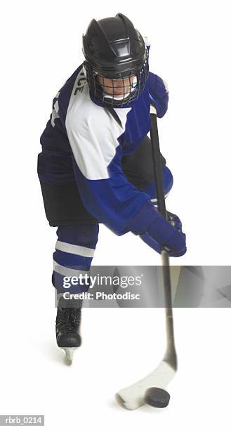 a child caucasian male hockey player dressed in a blue white and black jersey skates with his stick and puck - uniforme de hóquei no gelo imagens e fotografias de stock