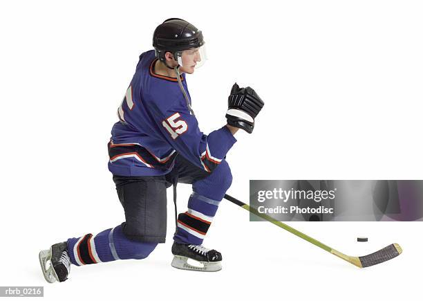 an adult caucasian male hockey player in a blue jersey speedily skates forward with his stick and puck - ice hockey uniform stock pictures, royalty-free photos & images
