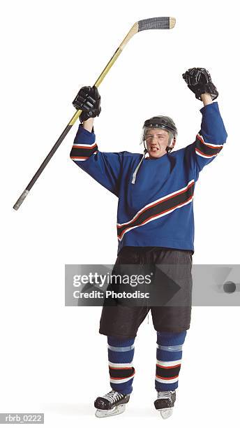 an adult caucasian male hockey player in a blue jersey raises his arms and stick to celebrate a goal - uniforme de hóquei no gelo imagens e fotografias de stock