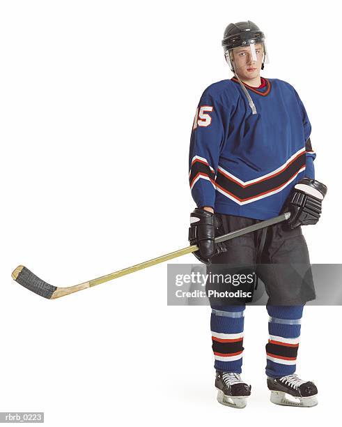 an adult caucasian male hockey player in a blue jersey stands with his stick extended and displays a stern look - goalie stick fotografías e imágenes de stock