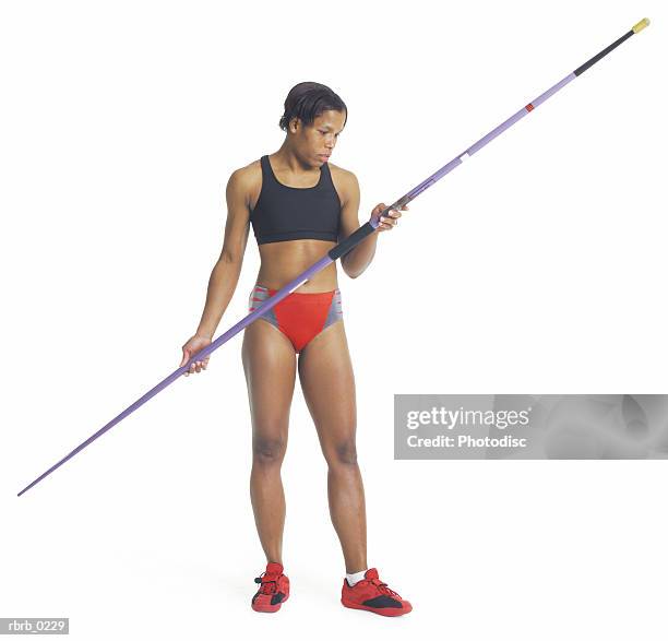 a young african american female athlete in red and black holds the javelin and prepares for the javelin throw - womens field event stockfoto's en -beelden