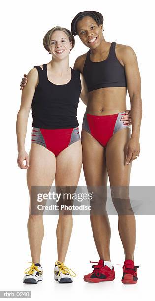 two track teammates a young caucasian female and a young african american female put their arms around each other wearing red shorts - running shorts foto e immagini stock