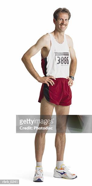 an adult caucasian male marathon runner in red shorts and a white tank stands smiling with hands on hips - la marathon - fotografias e filmes do acervo