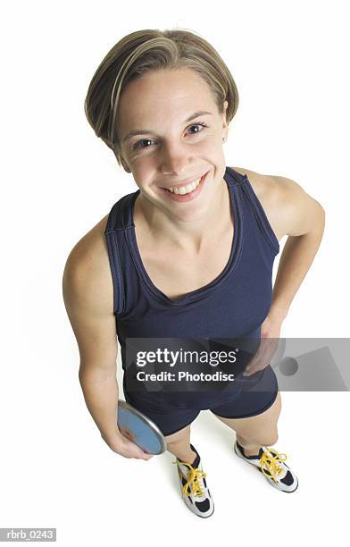 a young caucasian female track and field participant in a blue tank and shorts stands with a discus looking up at the camera - women's field event foto e immagini stock