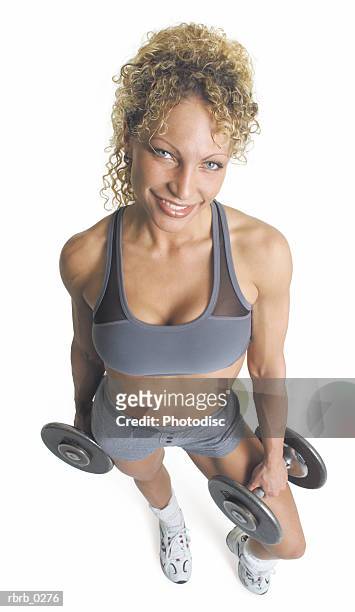 a curly haired blond female weightlifter is wearing gray and holding her dumbbells as she smiles looking up at the camera - curly stock pictures, royalty-free photos & images