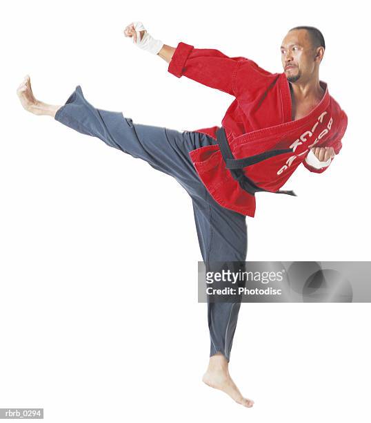 an asian male karate black belt wearing a red top and black pants is jumping and kicking to his right - championship belt stockfoto's en -beelden