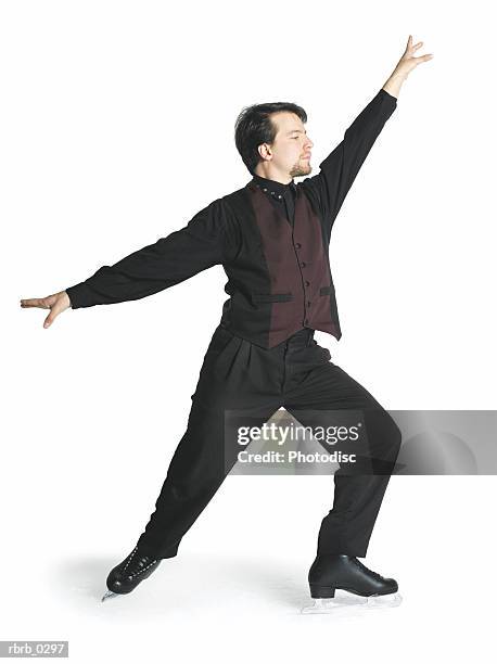 a caucasian male ice skater with a goatee is wearing a black outfit and maroon vest as he strikes a pose with arms outstretched - maroon - fotografias e filmes do acervo