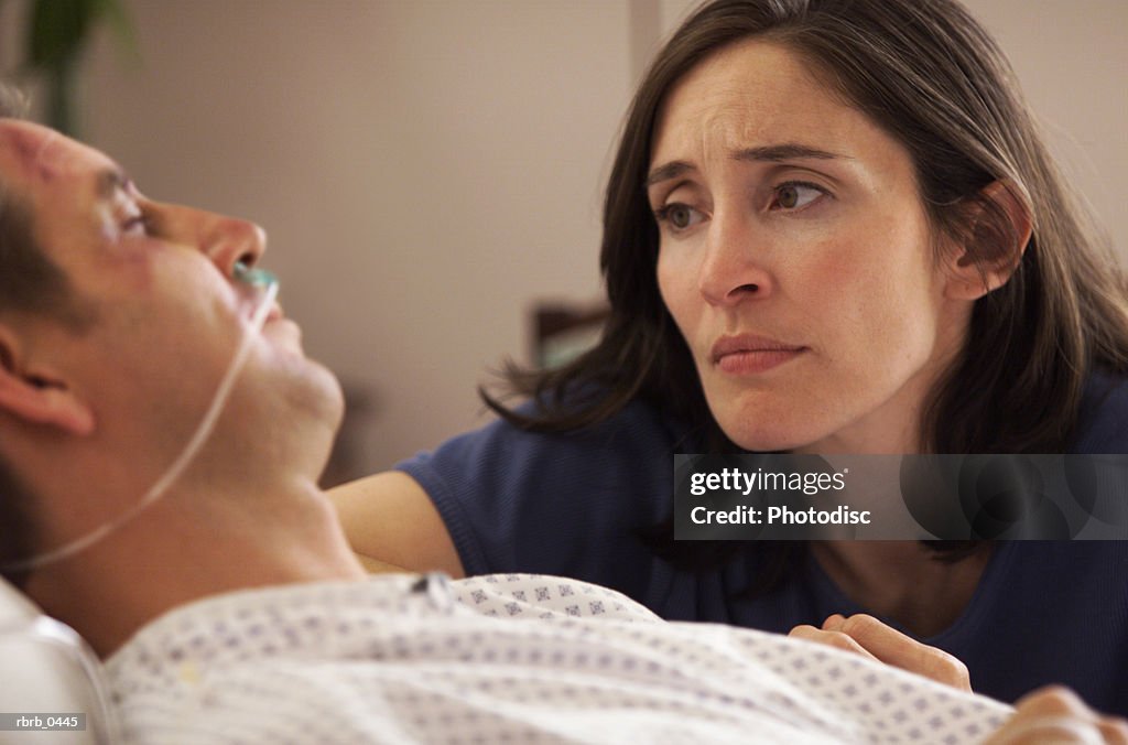 Lifestyle photo of a caucasian woman at the hospital bedside of her injured husband