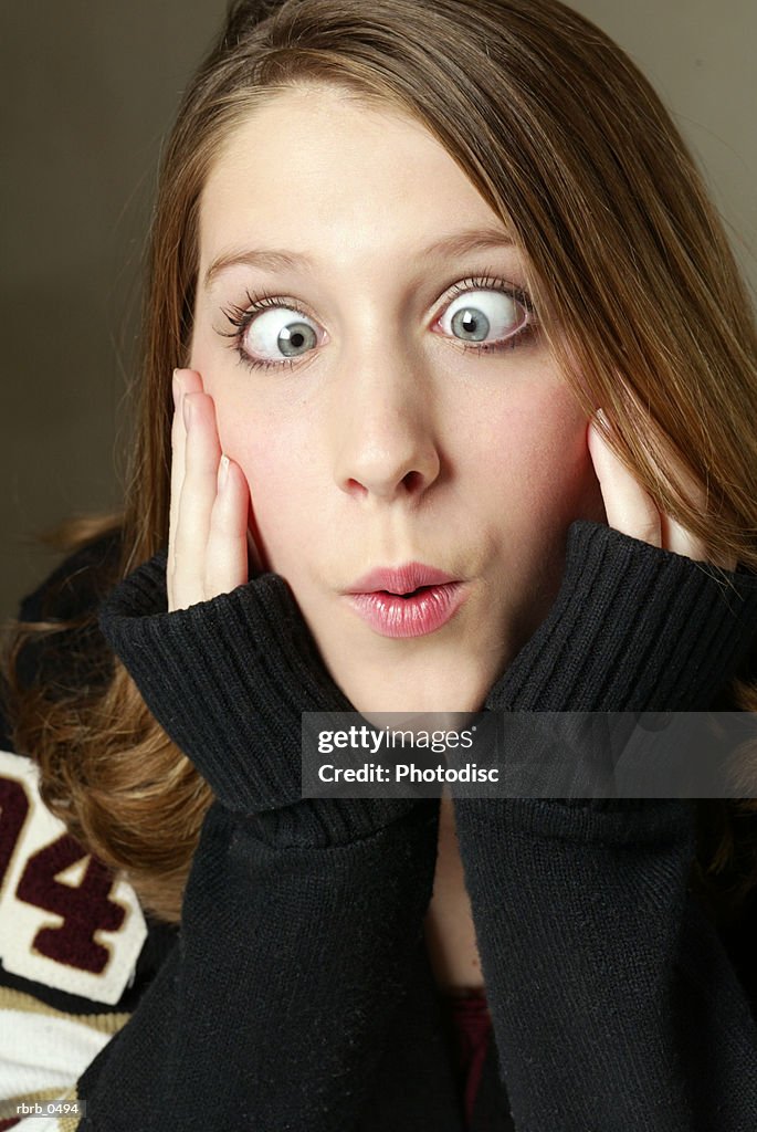 Studio portrait of a teenage caucasian girl in a black sweater as she makes a funny face