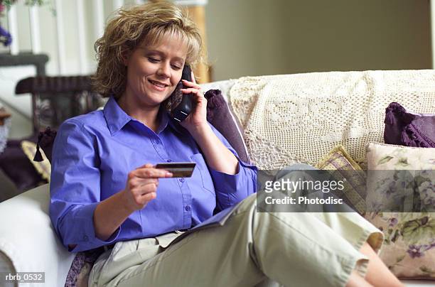 a blonde caucasian woman uses a credit card to purchase over the phone - uses stock pictures, royalty-free photos & images