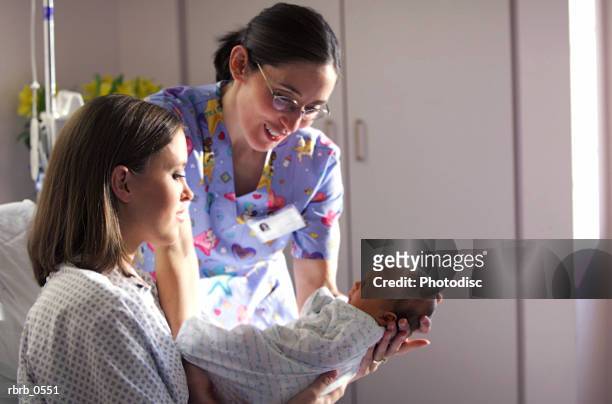 a caucasian mother shows off her newborn baby to a nurse while recovering in a hospital bed - nurse with baby stock pictures, royalty-free photos & images