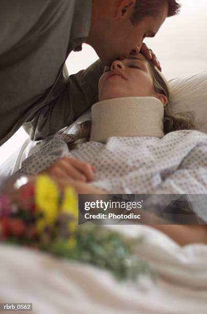 a caucasian man brings flowers to his injured wife as she lays in a hospital bed - (braces) stock pictures, royalty-free photos & images