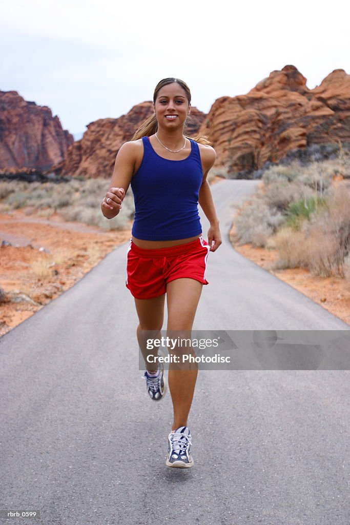 Shot of a young ethnic female athlete as she runs through a rural red rock setting