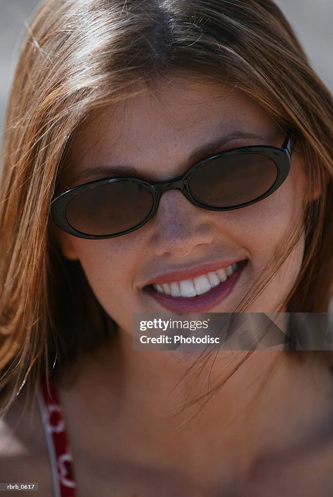 A young attractive caucasian female in sunglasses smiles into the camera