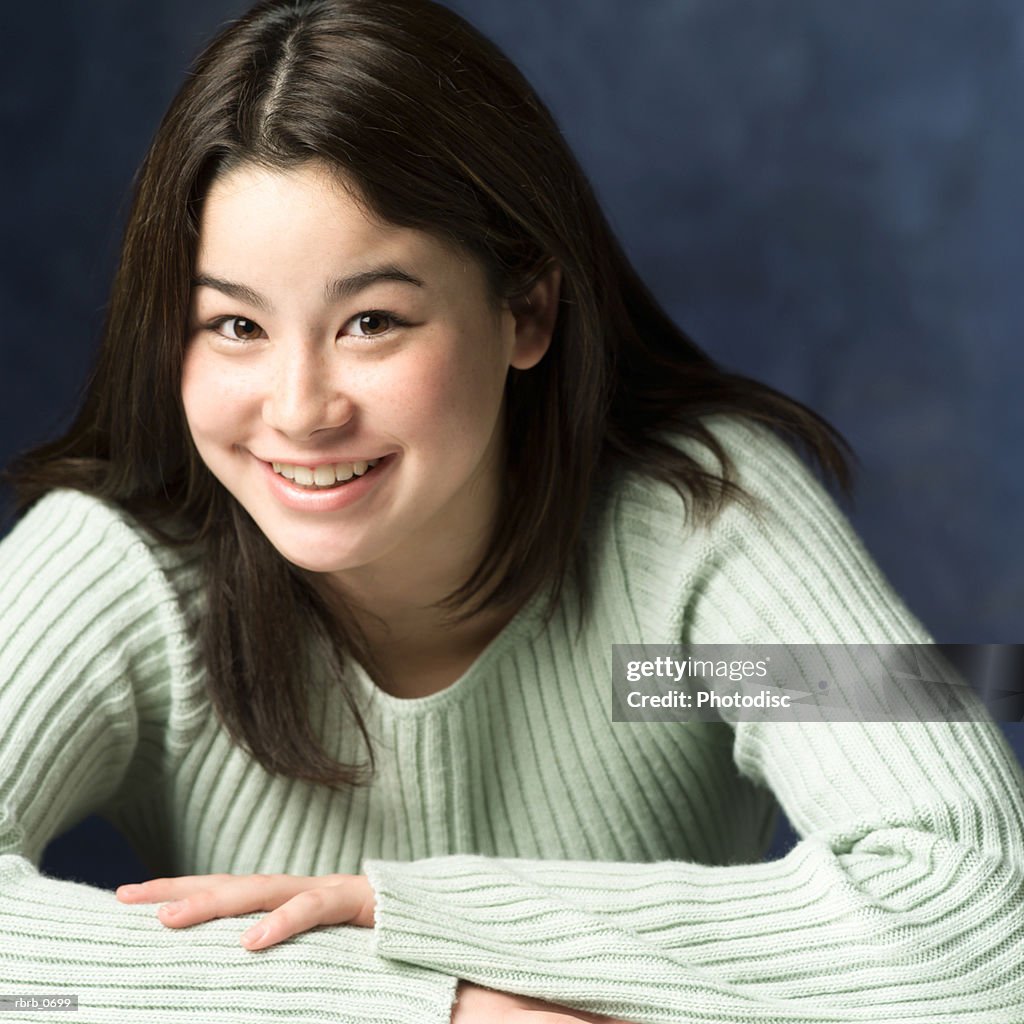 Portrait of an asian teenage girl in a green sweater as she crosses her arms and smiles