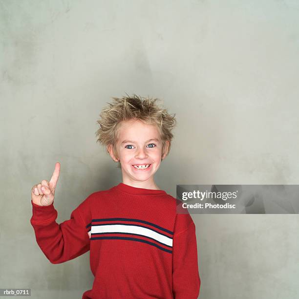 portrait of a caucasian male child in a red shirt as he points upward and smiles - spiky hair stock pictures, royalty-free photos & images