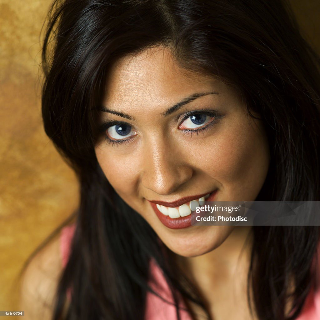 Portrait of a young attractive hispanic woman in a pink blouse as she smiles upward at the camera