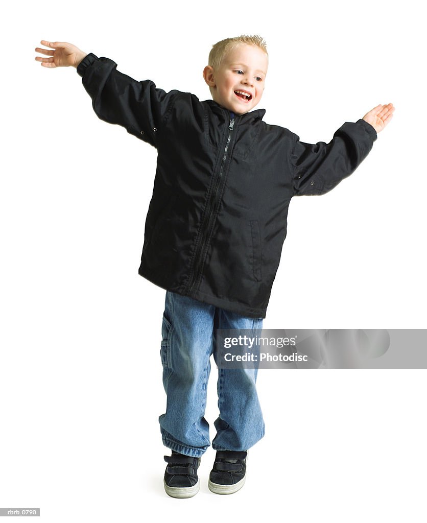 Blond caucasian boy jumping and similing with arms outstreached