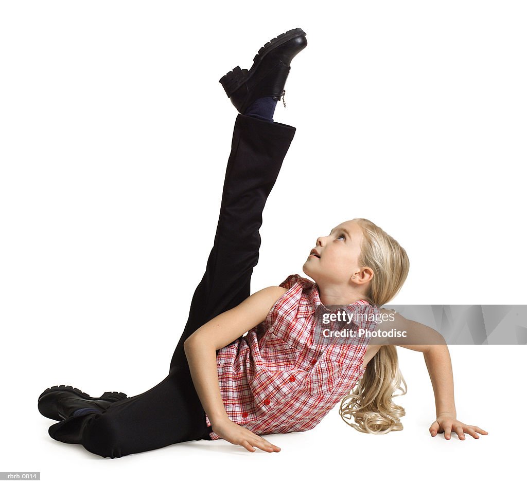Silhouette of a caucasian blonde female child  in black pants and a plaid shirt as she kicks up into the air
