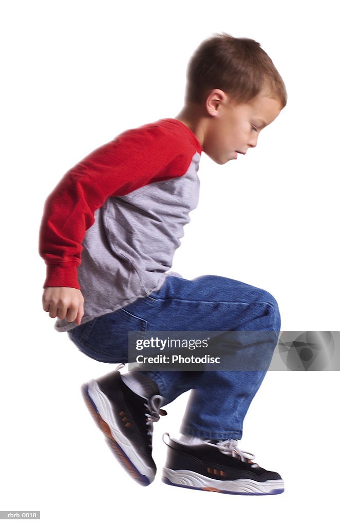 Silhouette of a caucasian male child in jeans and a red shirt as he jumps sideways through the air