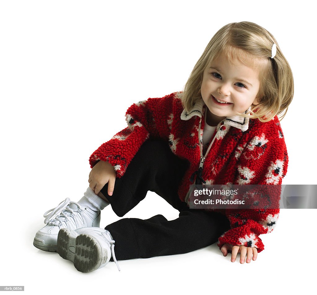 Silhouette of a cute caucasian female child in black pants and a red sweater as she sits and smiles